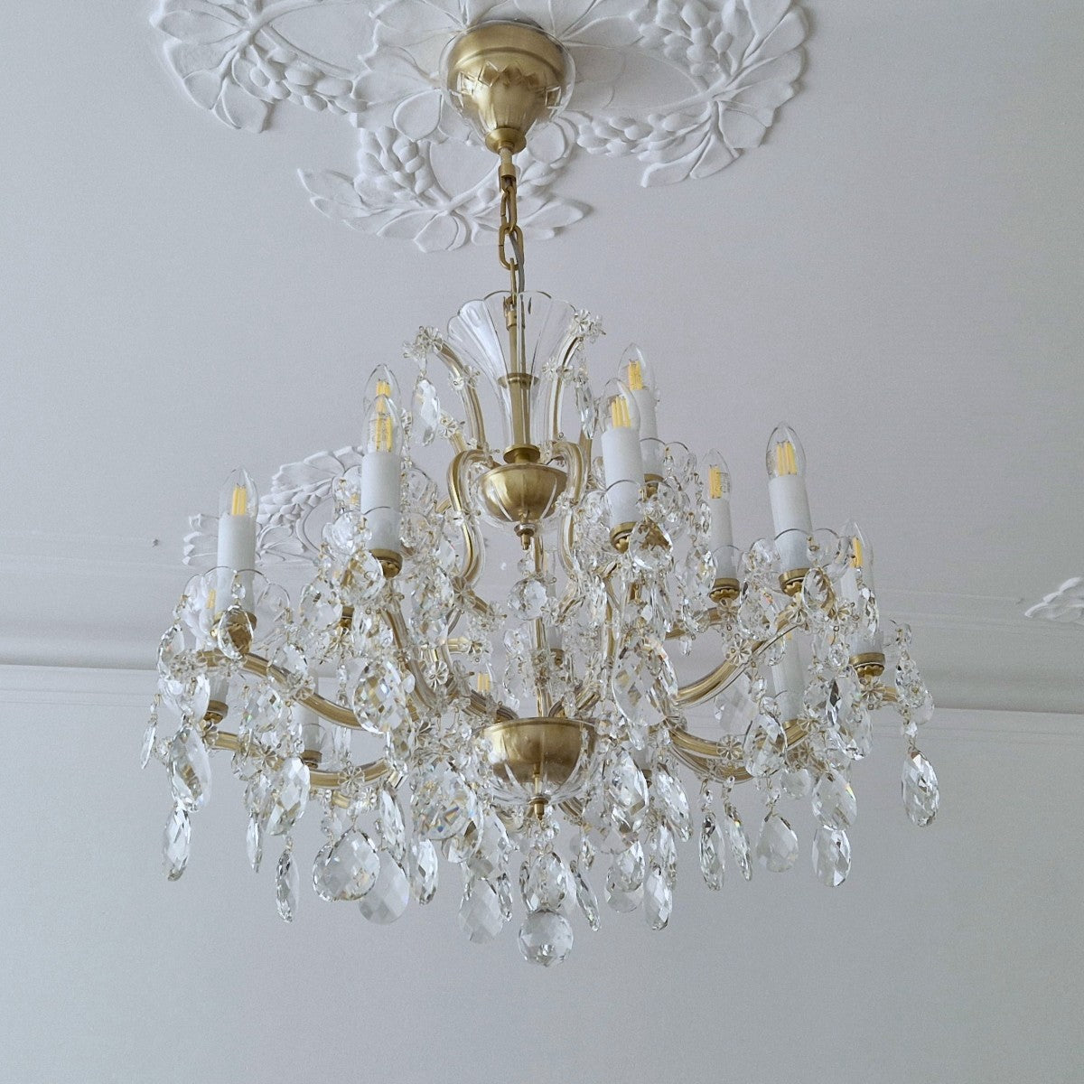 Gold chandelier with crystal accents against a white wall