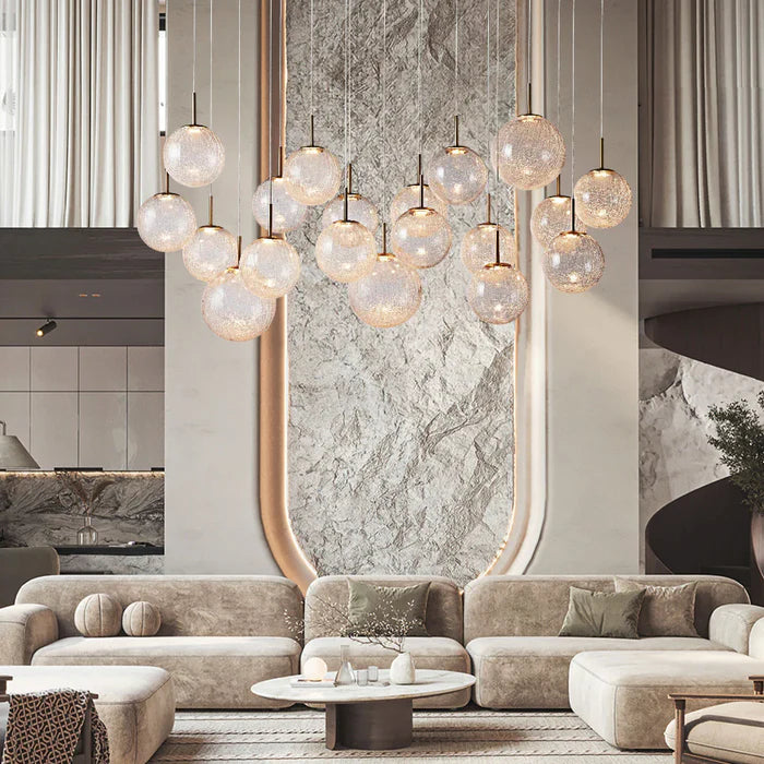 Modern living room with a large chandelier, marble wall, and beige sofa.