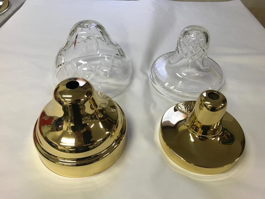 Two clear plastic baby bottle nipples with gold bases on a white surface.