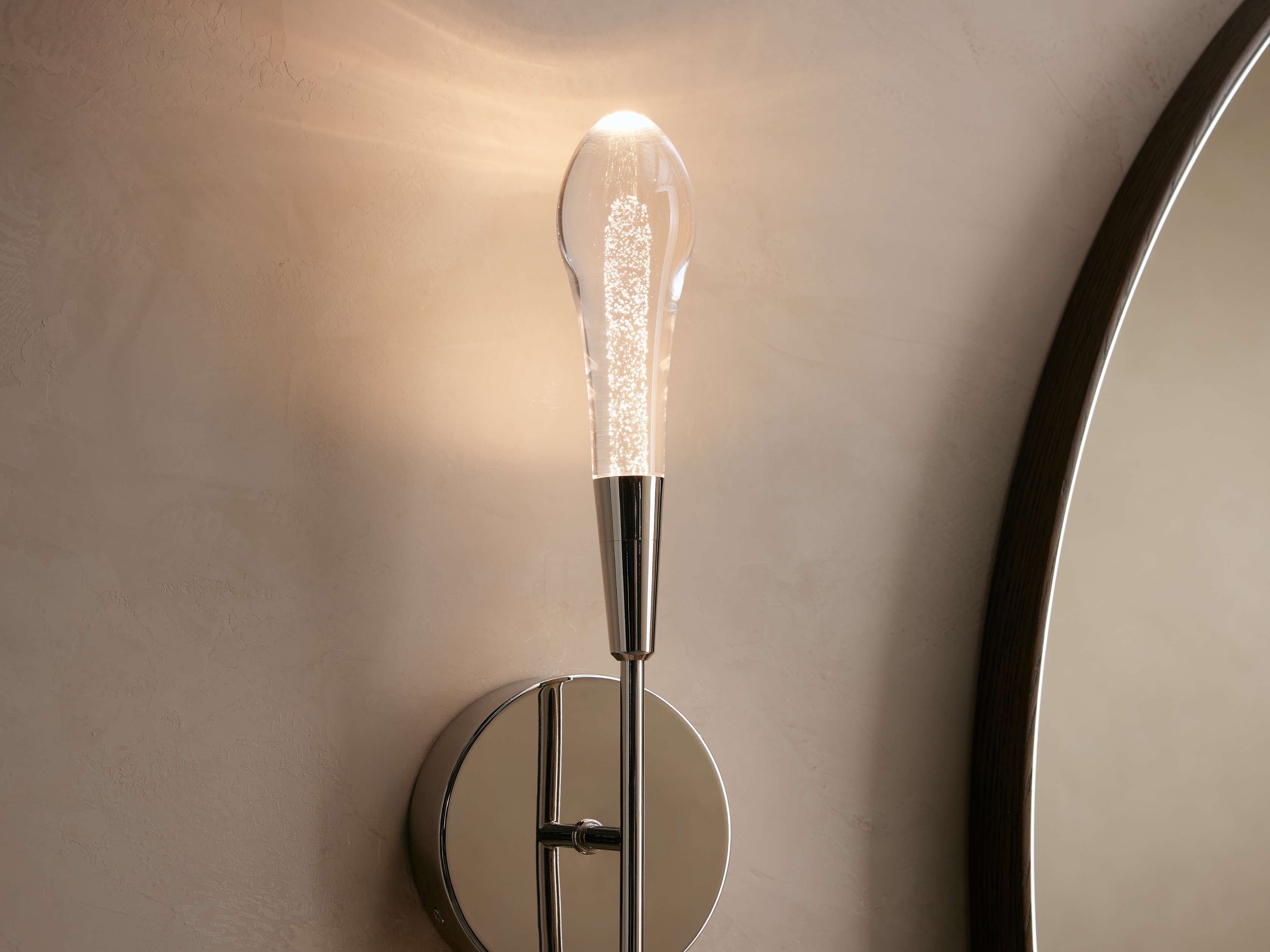 Wall-mounted light fixture with a glass bulb on a neutral wall.