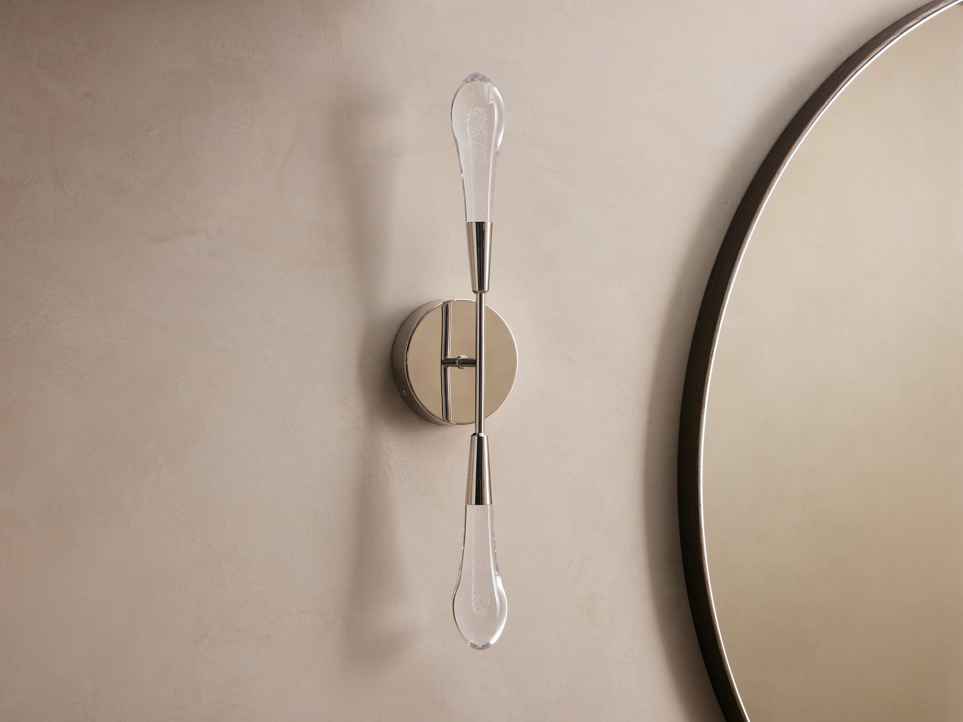 Decorative wall sconce with a round mirror on a beige wall