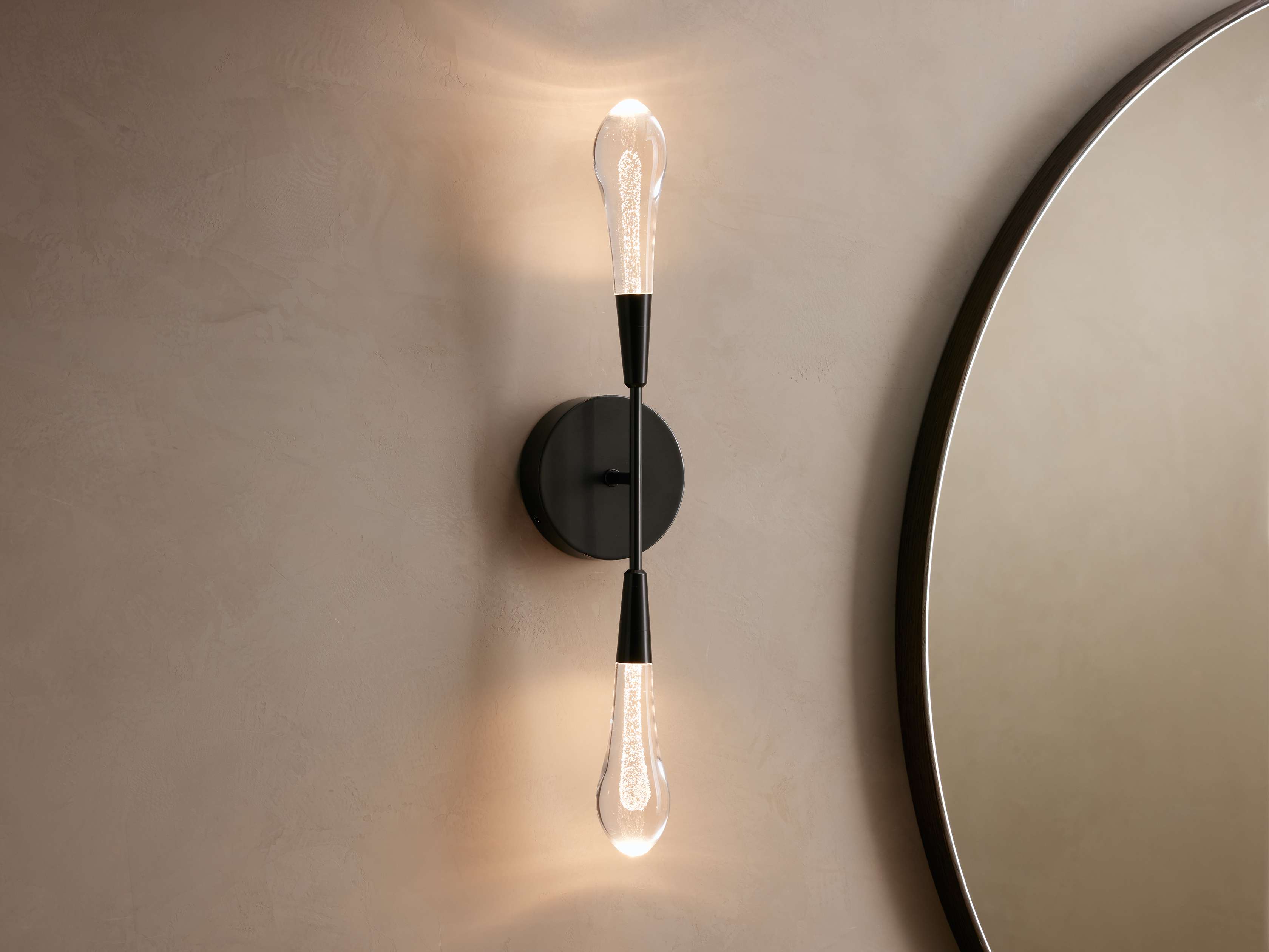 Gold wall sconce with two light bulbs on a neutral wall.